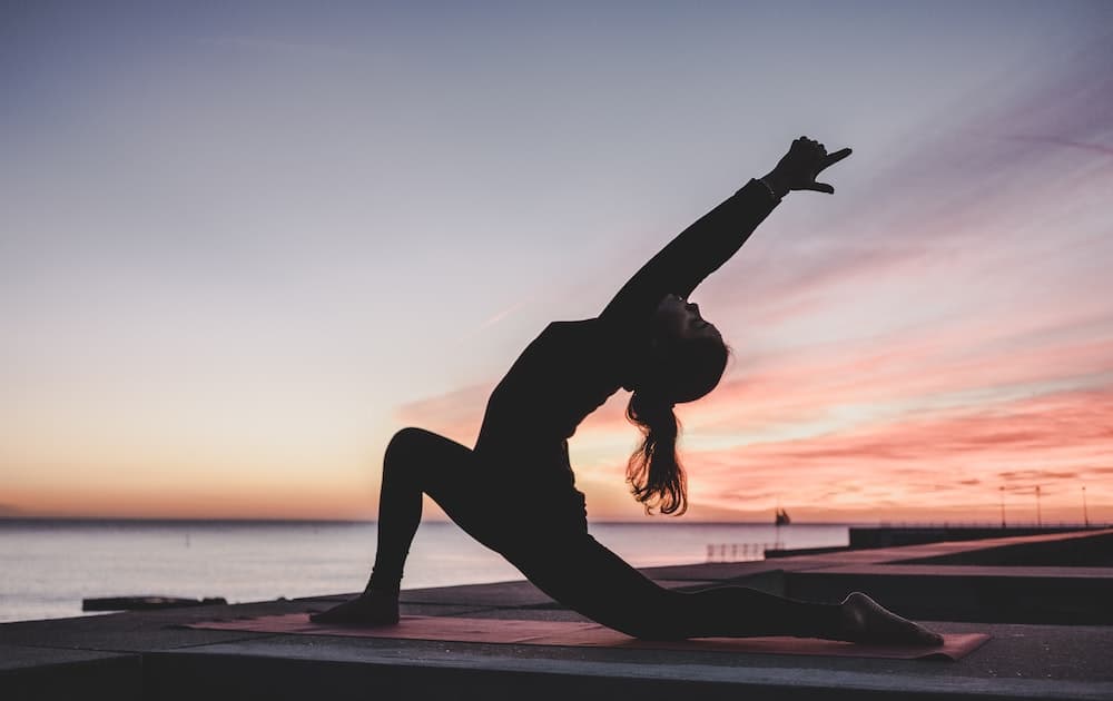 silhouette of woman doing yoga on the beach